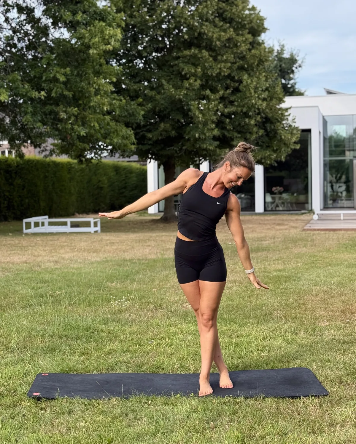 Ann-Sofie doet een Pilatesoefening op een mat in de tuin